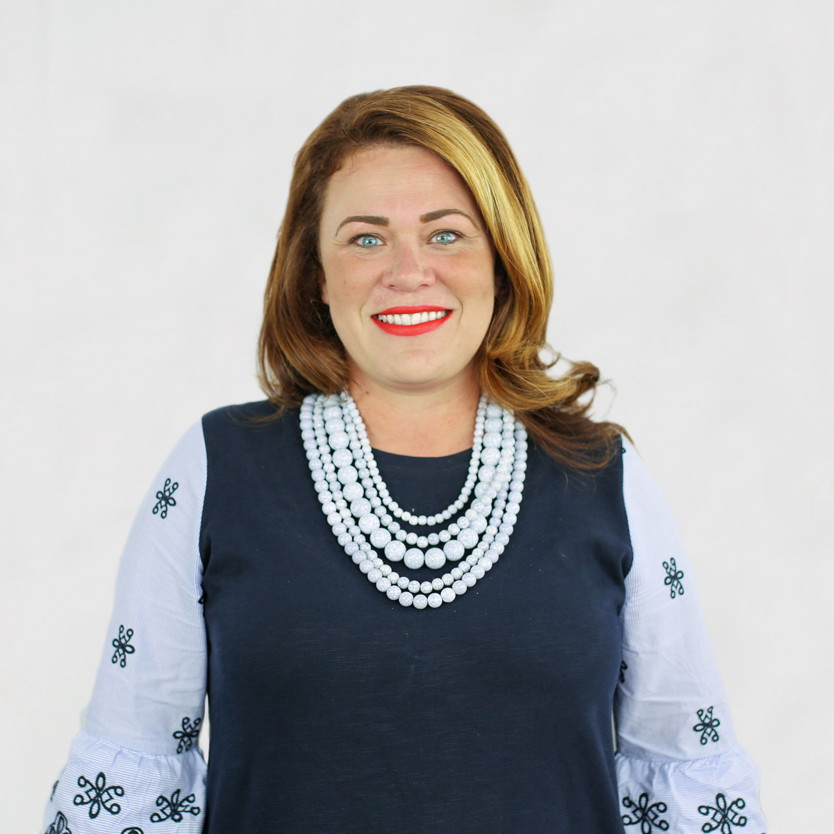 Sarah Dohl in a light blue and dark blue top with necklace